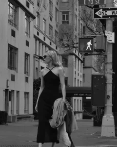 Mulher loira elegante com vestido preto em rua de Nova York, estilo clean girl aesthetic.
